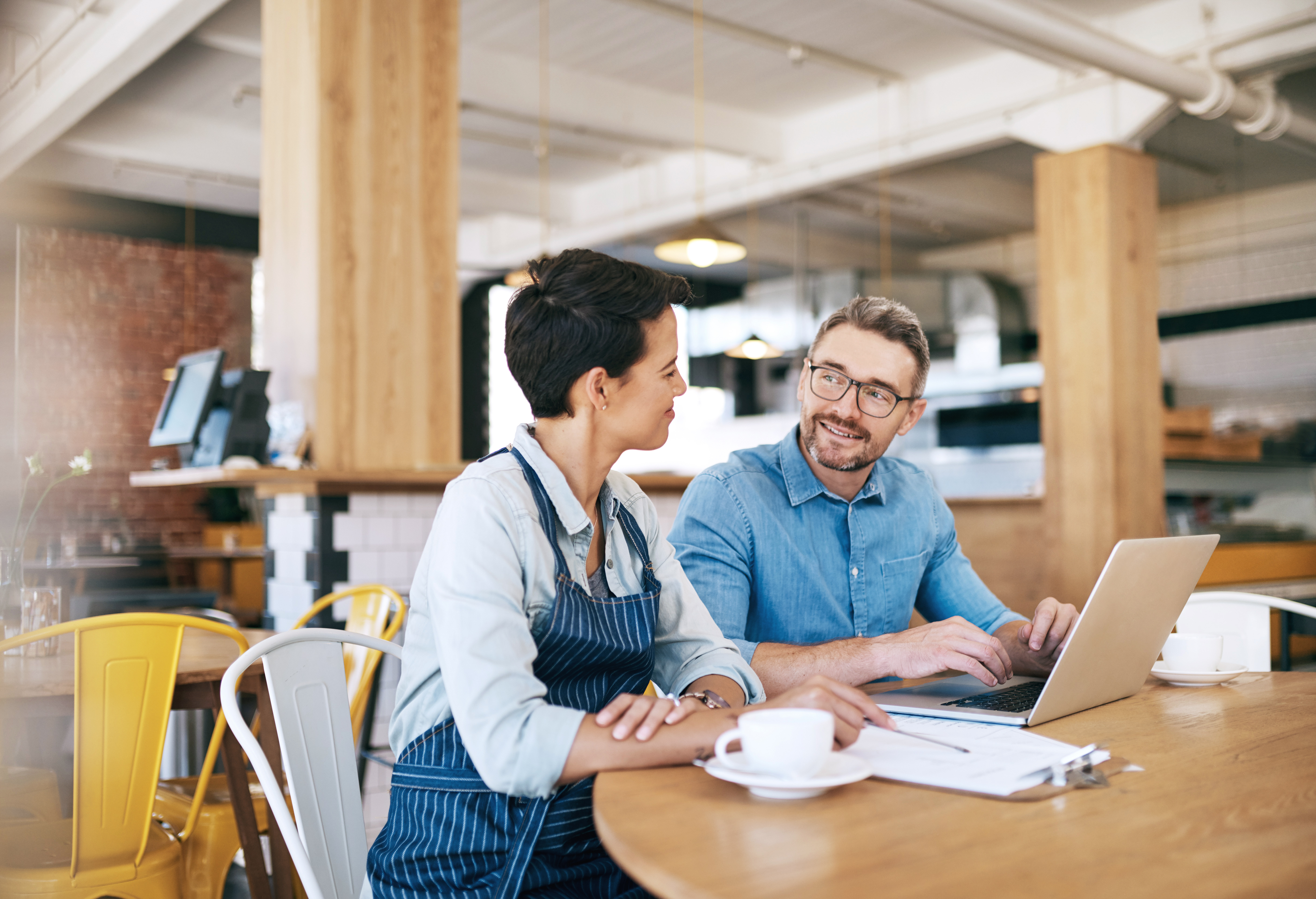 Cafe workers sit at a table in front of a laptop
