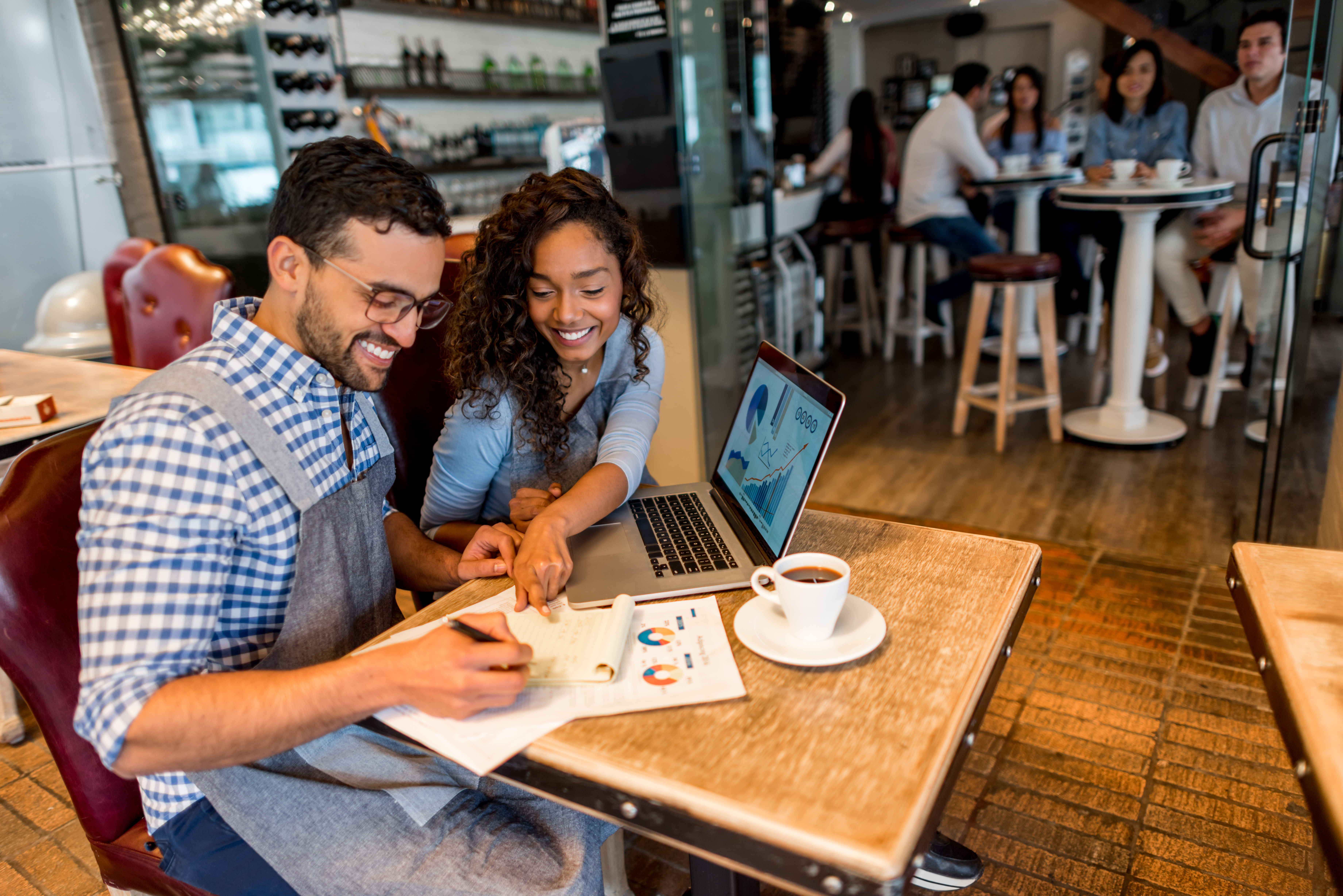 Man and woman smiling at a table with a laptop